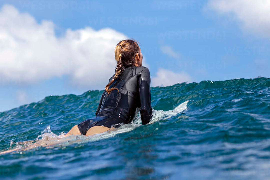 Women wearing wetsuit surfing in the sea