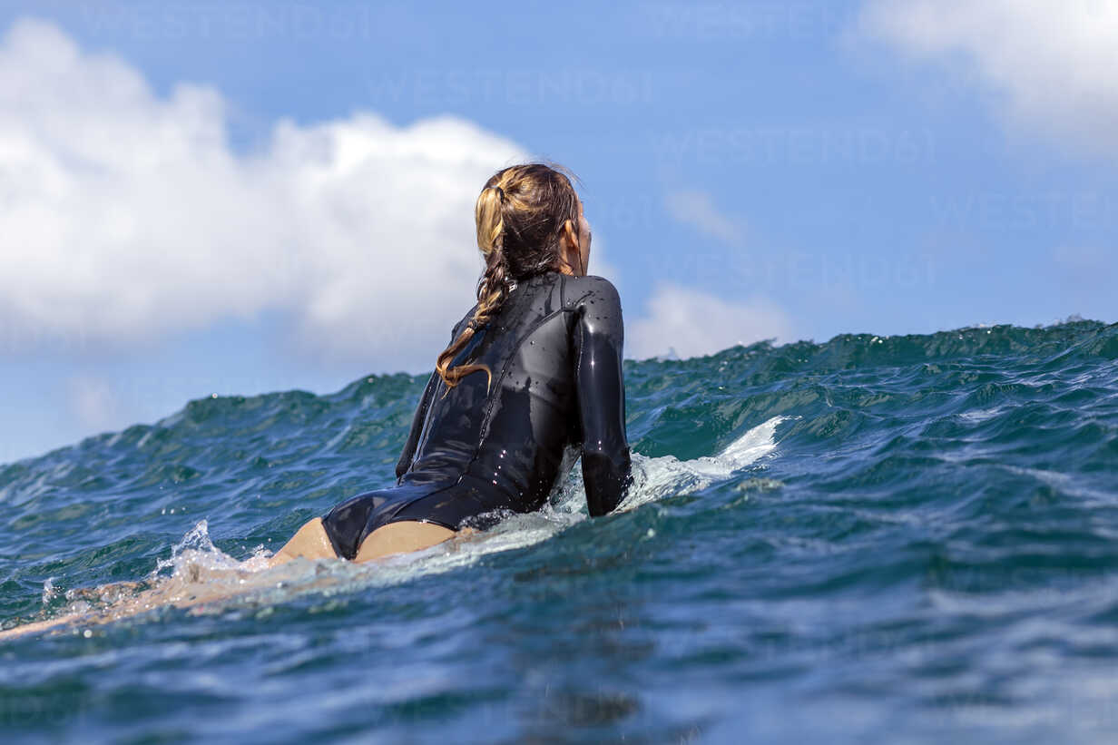 Women wearing wetsuit surfing in the sea