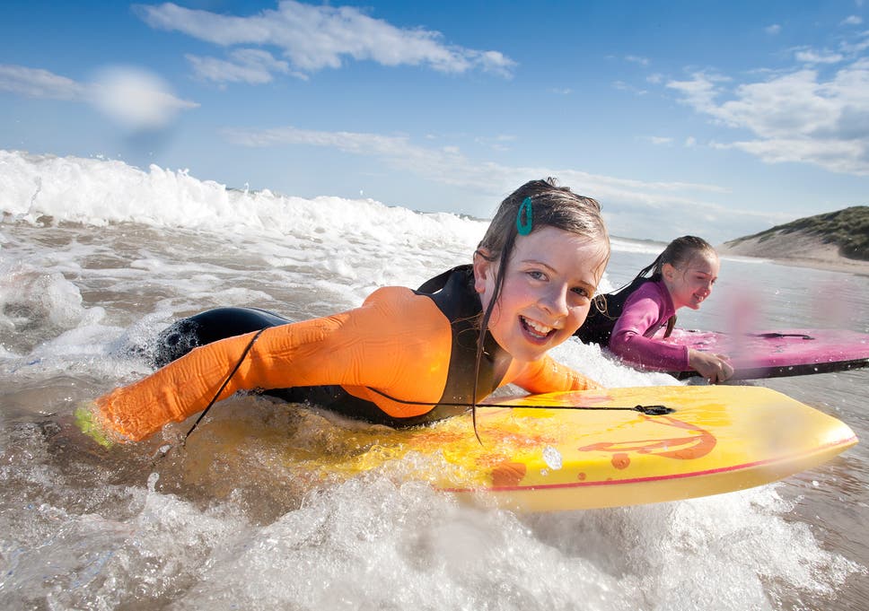 Children enjoying the waves while wearing surf wetsuits