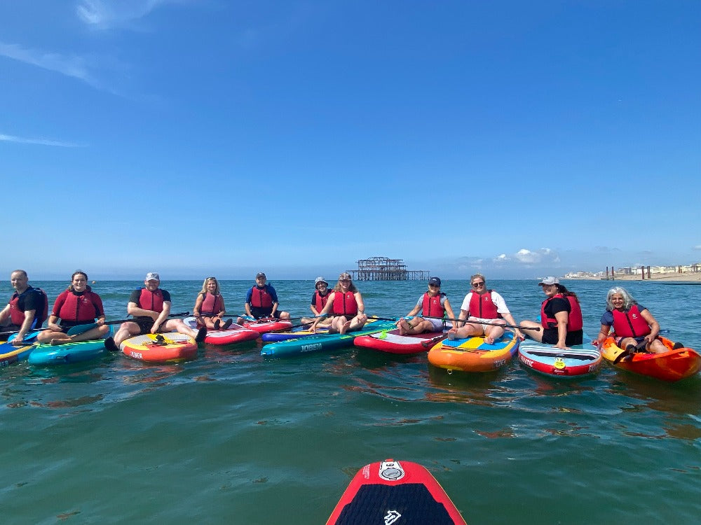Paddle board group on Brighton sea sitting on boards