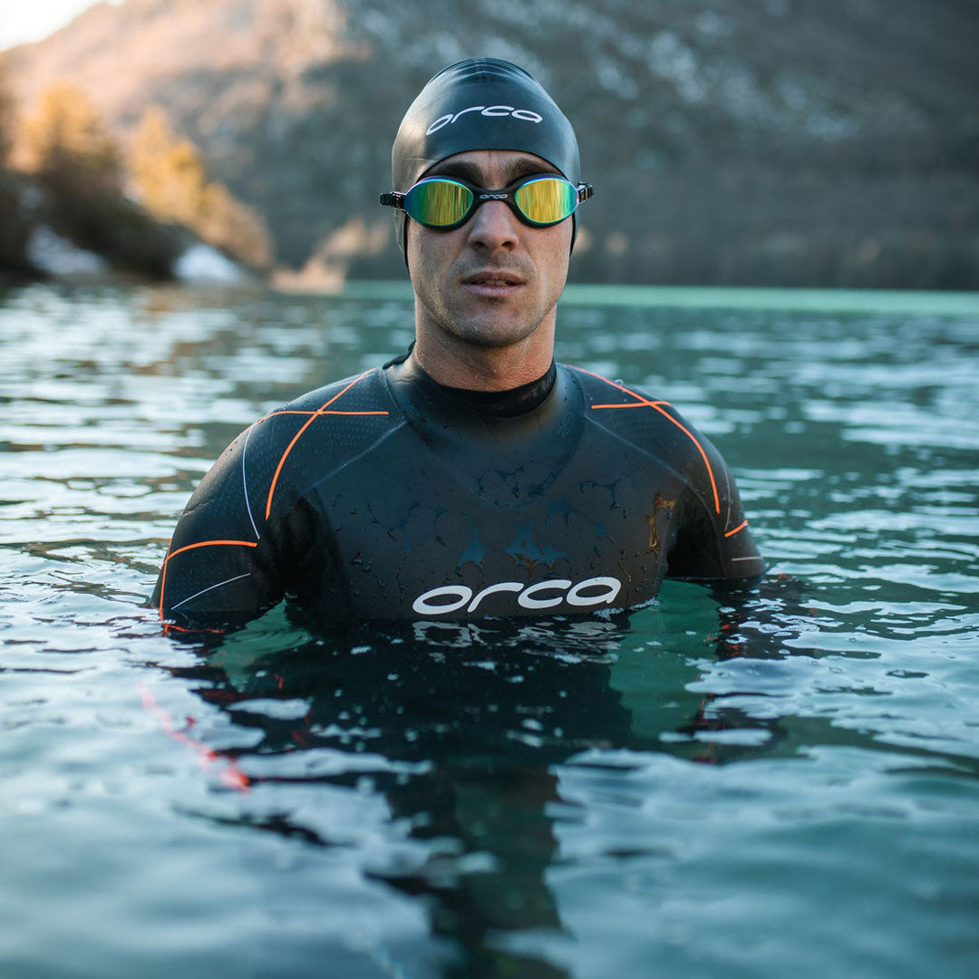 man in sea wearing orca wetsuit, swimming cap and googles