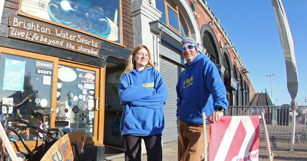 Two Brighton Watersports staff standing outside front shop