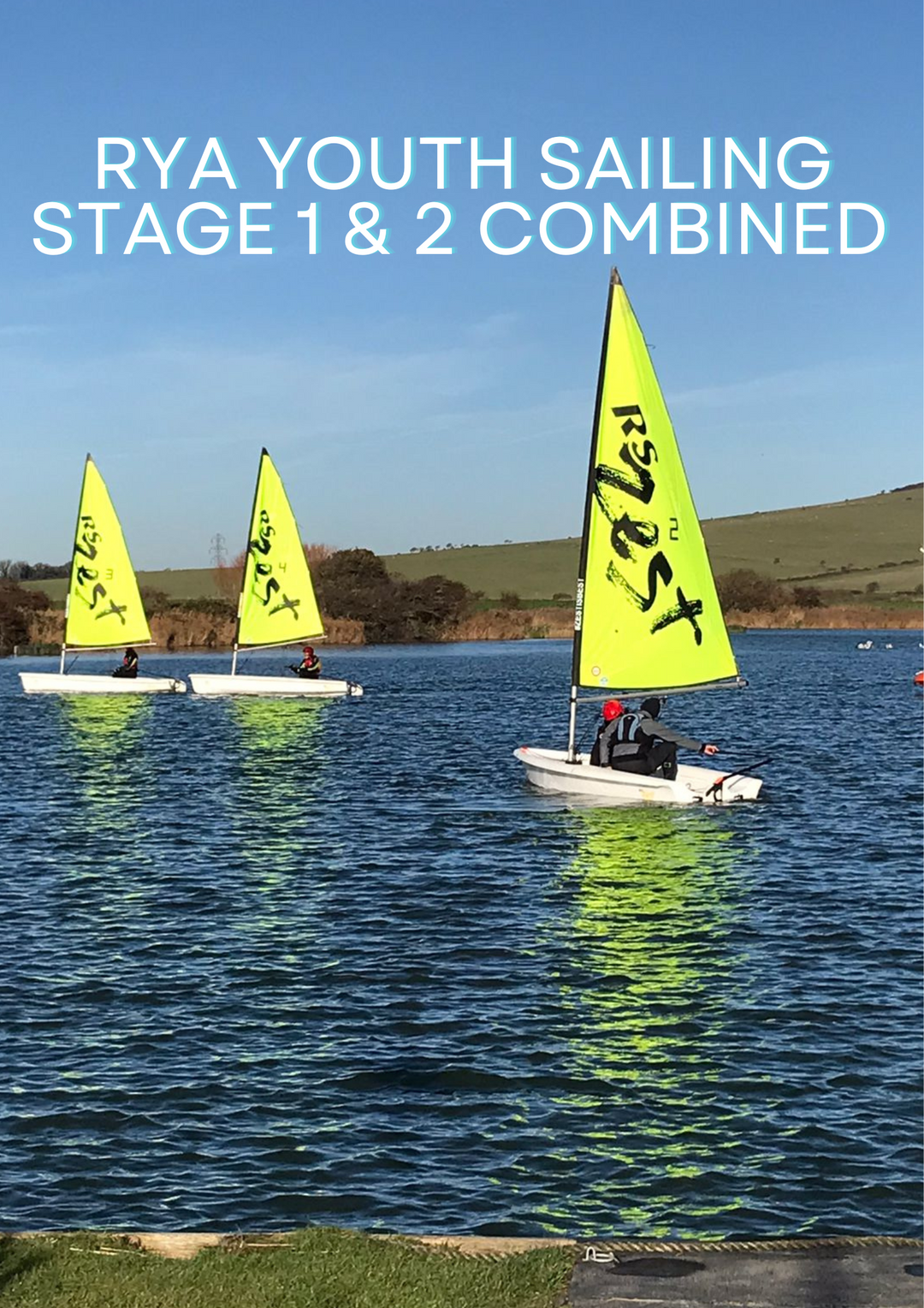 Two dinghy sailboats with bright yellow sails on Piddinghoe Lake, Brighton. One boat has a adult instructor and children sailing, and the other boat is seen further in the distance.